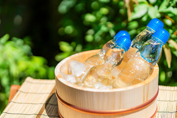強い夏の陽射しと木桶で冷える瓶ラムネ /...