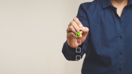 Businessman ticks the correct sign with yellow marks in checkboxes while standing on a gray background.