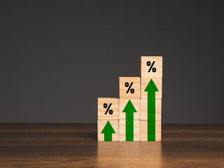 Interest rate financial concept. Wooden cubes with green arrows up and percentage symbols on a wooden table.
