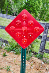 Diamond reflective red street sign for dead end with pasture and forest behind old fence