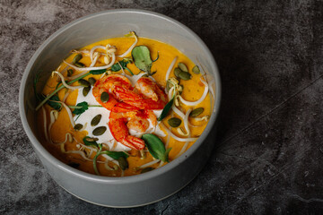 pumpkin cream soup with shrimp and cheese on black background 