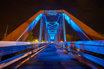 Bright neon blue lights on wooden walking bridge inside truss railroad bridge at night in Ohio