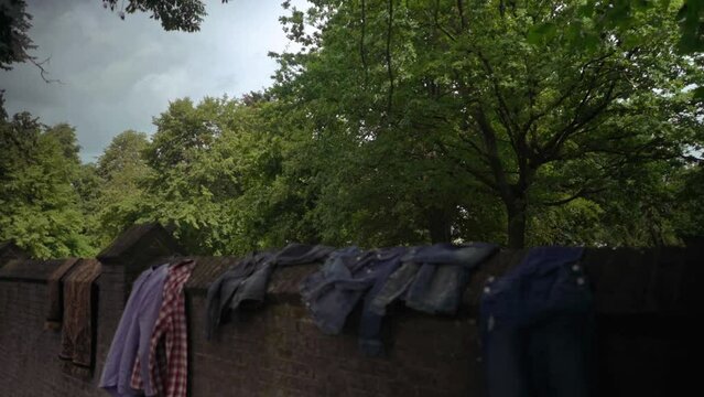 Revealing a graveyard behind a brickstone wall with clothes drying