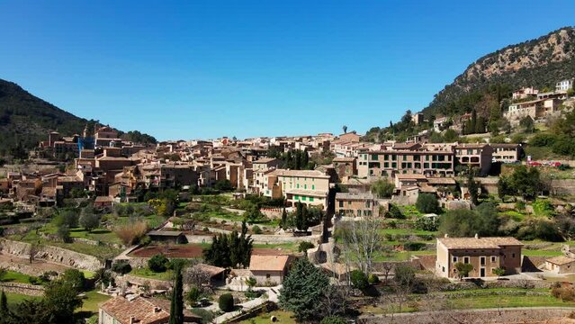Slow aerial drone reveal of historic Deia Village on span ish tropical island Mallorca
