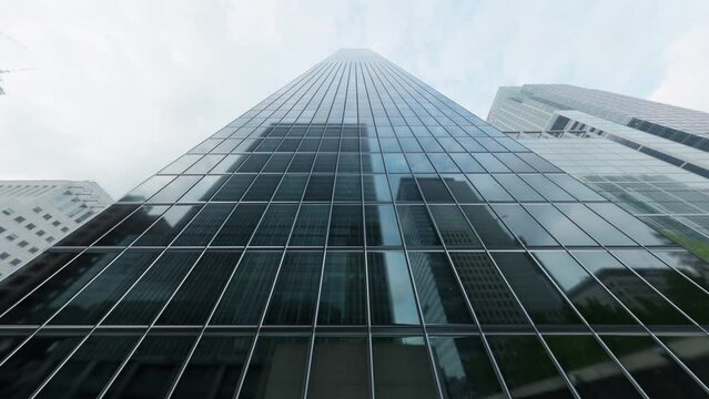 The camera spins around a skyscraper with mirrored windows in the heart of the business district. Seamless loop.