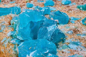 Gorgeous turquoise blue shards resting on a shore of broken clear glass fragments