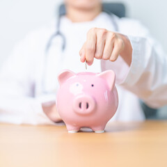 Doctor holding piggy bank and putting coin. and Healthcare cost, Money Saving, Health Insurance, Medical, Donation and Financial concepts