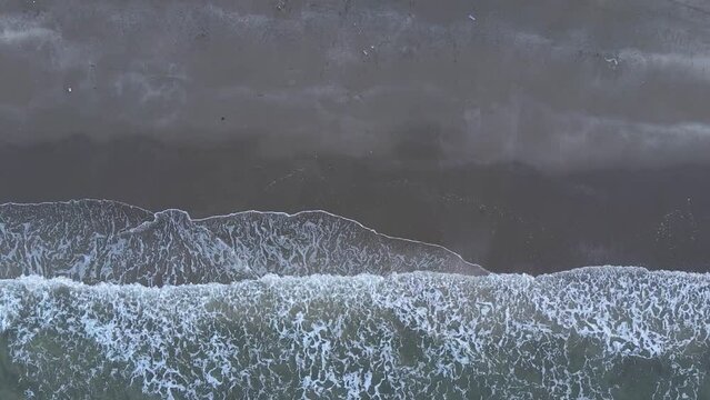Beautiful moment when the sun sets  over the sea waves that wash the beach sand. Cinematic drone footage of a sunset on an unspoiled beach in East Aceh, Indonesia