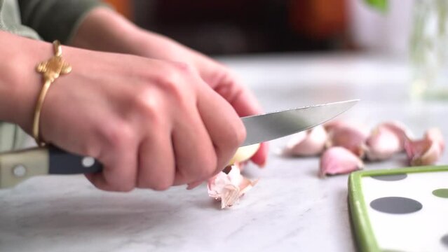 hand peeling garlic next to a sea bream and a whiting on the work surface