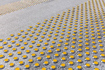 steps of a granite staircase with yellow tactile nonskid markings. closeup view.