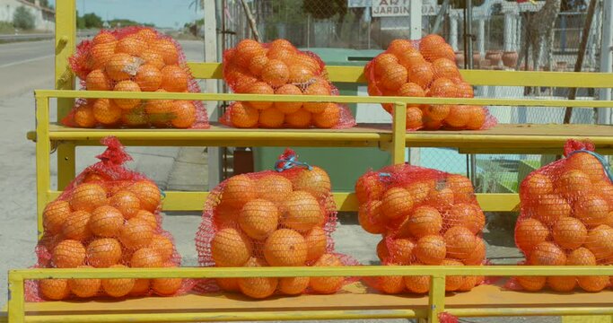 Fresh Mandarin Oranges In Net Bags For Sale At Fruit Stand By The Roadside In Spain. sideways