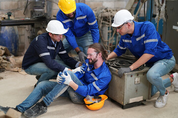 Worker receiving industrial injury in factory and colleague helping him while injured on leg.