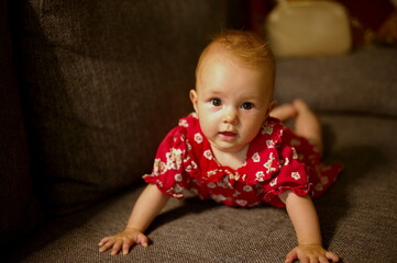 Naklejka premium Closeup portrait of cute little baby girl lying on a sofa