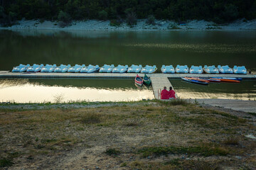 A row of white catamarans for skating on a calm evening lake in the sunlight. Active lifestyle in...