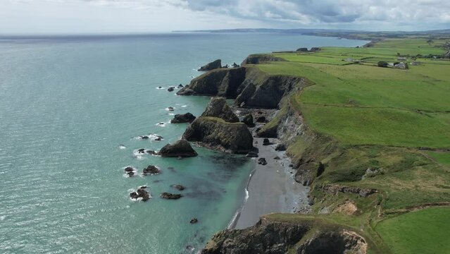 Drone flying west along The Copper Coast Waterford Ireland over the sea stacks that line the coast on a warm July day