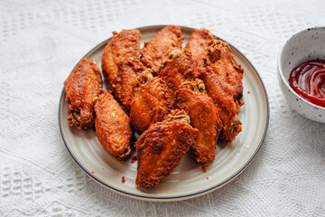Fried chicken wings on a plate with tomato sauce