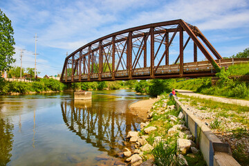 Summertime with Kokosing River in Ohio with person sitting and old railroad walking bridge