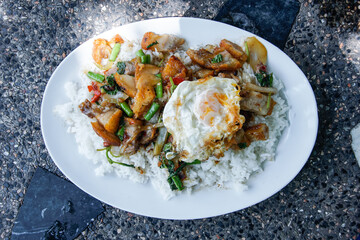 Stir-fried basil with crispy pork and fried egg topped with rice in a ready-to-eat dish.