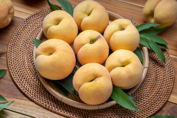 Yellow Peach on wooden basket,  Peach with leaf on wooden background.