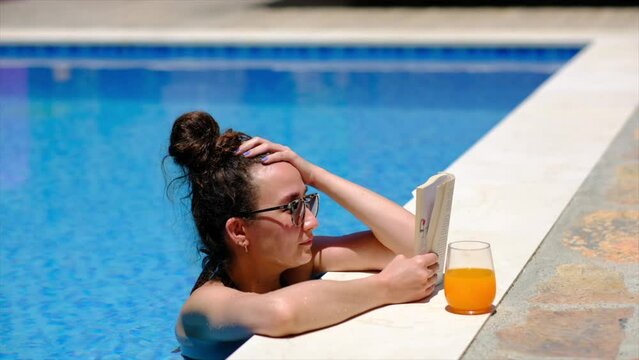 woman is reading a book by the pool