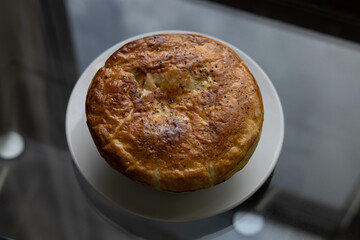 Home made chicken pot pie on a glass table next to a window at sunset