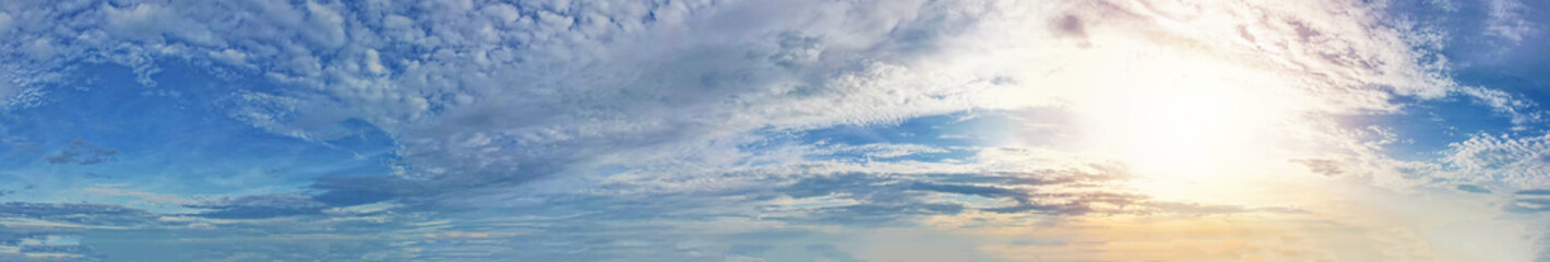 Breathtaking panorama unfolds, showcasing a vast blue sky dotted with gracefully wavy clouds, illuminated by the radiant sunlight.