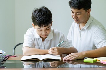 Fototapeta na wymiar Asian father helps son to do her homework for the school..child study together homeschooling concept getting homework help from father