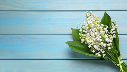 Beautiful lily of the valley bouquet on light blue wooden table, top view. Space for text