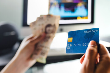 Financial Man holding credit card for shopping online with desktop computer at background in Mexico Latin America
