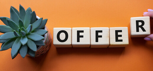 Offer symbol. Wooden cubes with word Offer. Businessman hand. Beautiful orange background with...