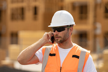 Builder in helmet call with phone on construction site. Construction engineer worker in builder...