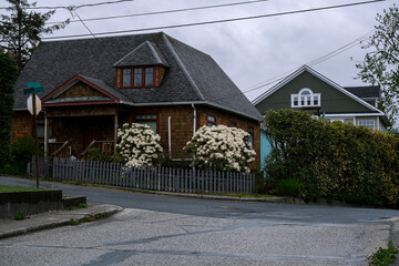 Fototapeta na wymiar Street city view with wooden houses, shops, cars and mountain wilderness nature in Sitka, Alaska, popular cruise destination for whale watching and wildlife tours Baranof Island