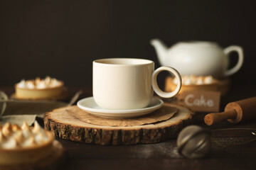 Still life with a cup of tea with milk, flowers and a teapot in the background