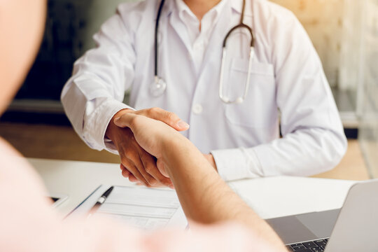 Doctor shaking hands with older patient in the clinic room.