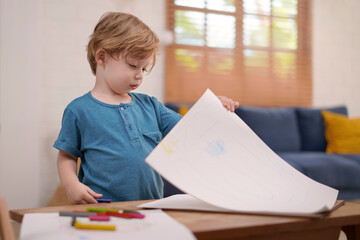 Little boy drawing with colored pencils at home.