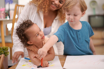 Mother and daughter with little boy drawing with colored pencils on paper at home. Happy family time.