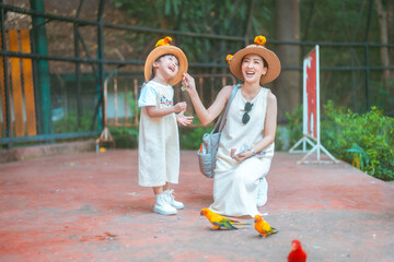 cute mom and baby girl in dress and hat with activity feed food bird