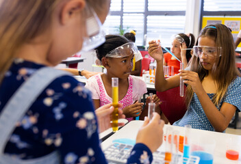 Diverse schoolgirls with chemistry items and liquids in elementary school class