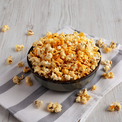 Homemade Pop Corn with Cheese in a Bowl on a white wooden background, side view.