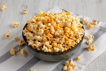 Homemade Cheesey Pop Corn in a Bowl on a white wooden background, side view.