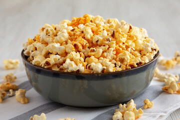Homemade Pop Corn with Cheese in a Bowl on a white wooden background, side view. Close-up.