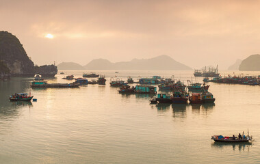 Fototapeta premium Colorful fishing boats on a sea near to rock islands on sunset. Ha Long Bay, Vietnam.