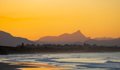 Sunset view of surfers in silhouette along the Belongil Beach area in Byron Bay, New South Wales,...