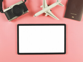 flat lay of digital tablet with blank white screen, airplane model, passport and digital camera isolated on pink background. travel planning concept.