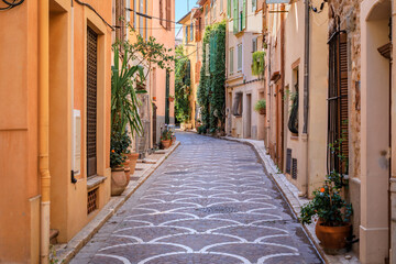 Ornate mosaic street pavement between traditional old houses near the covered provencal farmers market in old town or Vieil Antibes, South of France