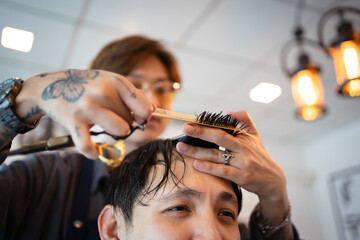 Handsome Asian man having a haircut at street hairdresser shop, professional street hair dresser -...