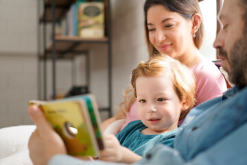 Happy family reading story book on bedroom at home. Relax time and Education Concept.