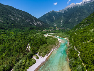 Soca Valley, Slovenia - Aerial view of the emerald alpine river Soca on a bright sunny summer day with Julian Alps, blue sky and green foliage