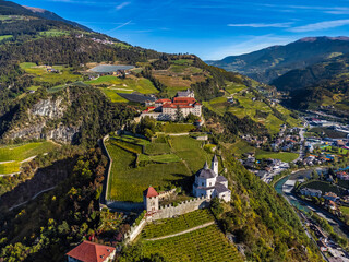 Klausen, Italy - Aerial view of the Säben Abbey (Monastero di Sabiona) with Chiusa (Klausen) comune northeast of the city of Bolzano and South Tyrol Dolomites at background on a sunny summer day