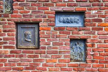 Fototapeta na wymiar Tall red brick wall with multiple cultural motifs and cameos background asset
